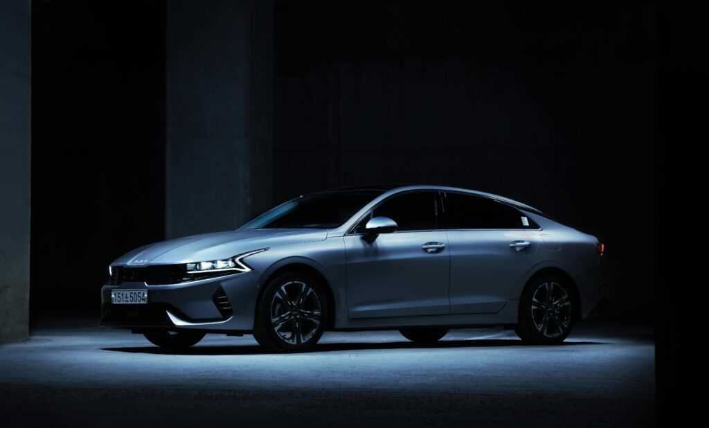 Sleek Kia K5 sedan showcased in a dimly lit indoor parking space.